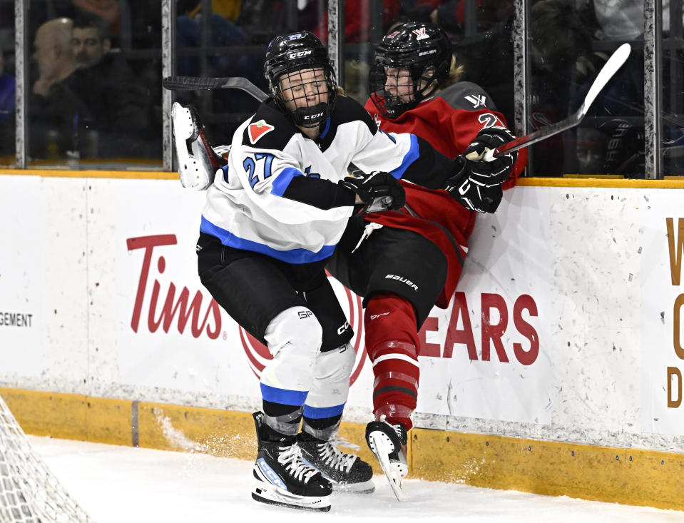 Toronto's Emma Maltais (27) sends Ottawa's Ashton Bell (21) into the boards during first-period PWHL hockey game action in Ottawa, Ontario, Saturday, March 2, 2024. (Justin Tang/The Canadian Press via AP)