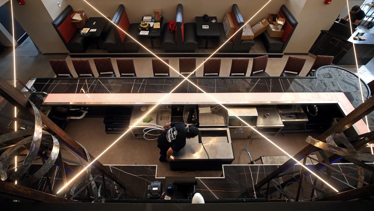 A worker installs bar equipment Thursday at Crave's new location in the Landmark Building downtown on Main Street.