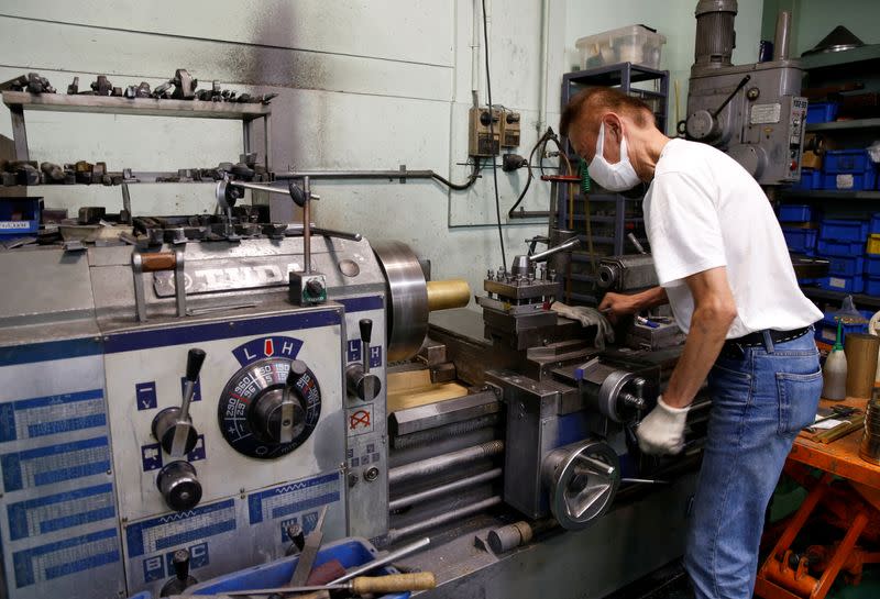 A man handles a machine at lampshade manufacturer Seiko SCM in Higashiosaka