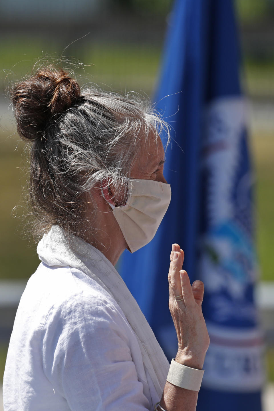 Tamara Sheen, originally from England, is sworn in as a new citizen outside the U.S. Citizenship and Immigration Services building, Thursday, June 4, 2020, in Lawrence, Mass. The federal agency is resuming services in many cities across the country after being shuttered for more than two months because of the coronavirus pandemic. (AP Photo/Elise Amendola)