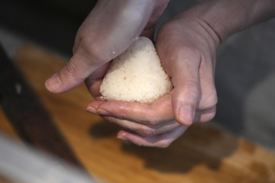 Yosuke Miura shapes the rice into a triangle at Onigiri Asakusa Yadoroku, Tokyo's oldest onigiri restaurant, on June 3, 2024, in Tokyo. The word "onigiri" just became part of the Oxford English Dictionary this year. The humble sticky-rice ball, a mainstay of Japanese food, has entered the global lexicon. (AP Photo/Eugene Hoshiko)