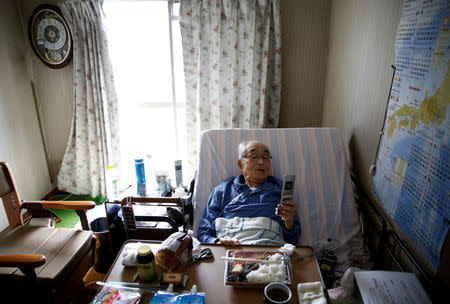 Katsuo Saito, 89, who has leukaemia, uses his mobile phone in his bed at his home in Tokyo, Japan, September 8, 2017. REUTERS/Kim Kyung-Hoon