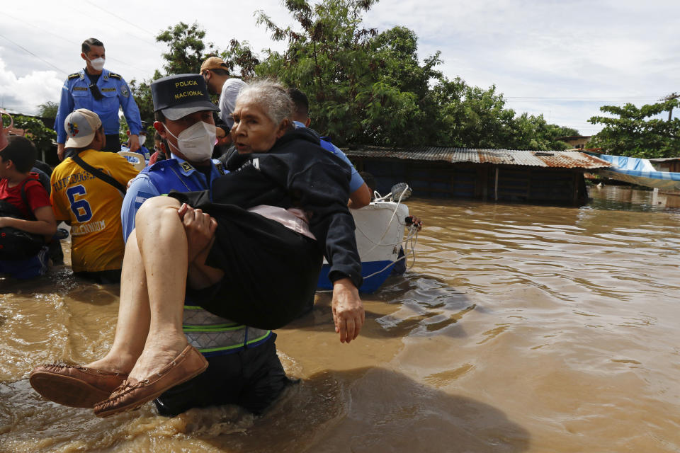 A National Police officer carries an elderly woman out of an area flooded by water brought by Hurricane Eta in Jerusalen, Honduras, Thursday, Nov. 5, 2020. The storm that hit Nicaragua as a Category 4 hurricane on Tuesday had become more of a vast tropical rainstorm, but it was advancing so slowly and dumping so much rain that much of Central America remained on high alert. (AP Photo/Delmer Martinez)