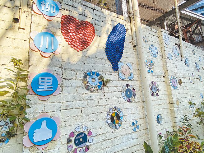柳川古道的牆壁上都是里內環保志工隊所回收的寶特瓶蓋、黑膠唱片、光碟、廢輪胎等，經過巧思後廢物再利用，作為社造的應用媒材。（張妍溱攝）