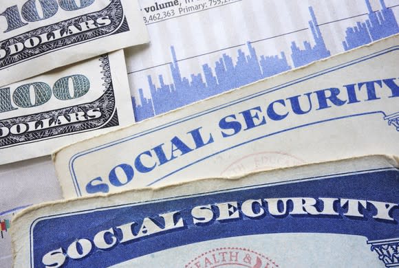 portions of social security cards and hundred dollar bills visible on a flat surface