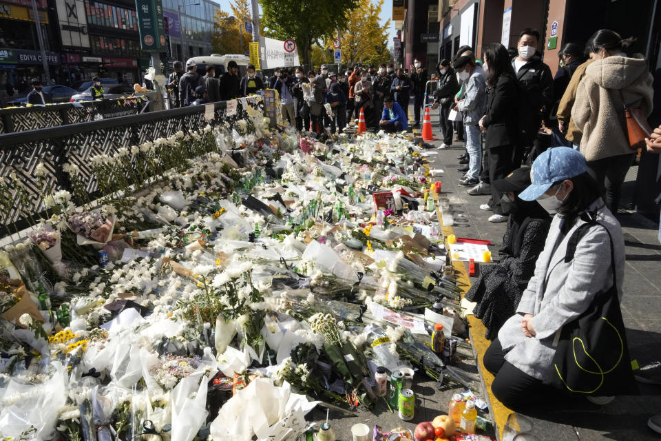 People pay tribute to victims of a deadly accident during Saturday night's Halloween festivities, at a makeshift flower-laying area set up near the scene of the accident in Seoul, South Korea, Wednesday, Nov. 2, 2022. South Korean officials admitted responsibility and apologized on Tuesday for failures in preventing and responding to a Halloween crowd surge that killed more than 150 people and left citizens shocked and angry. (AP Photo/Ahn Young-joon)