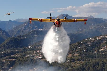 A Canadair firefighting aircraft drops water on a wildfire which burns a forest in Carros, near Nice, France. REUTERS/Eric Gaillard