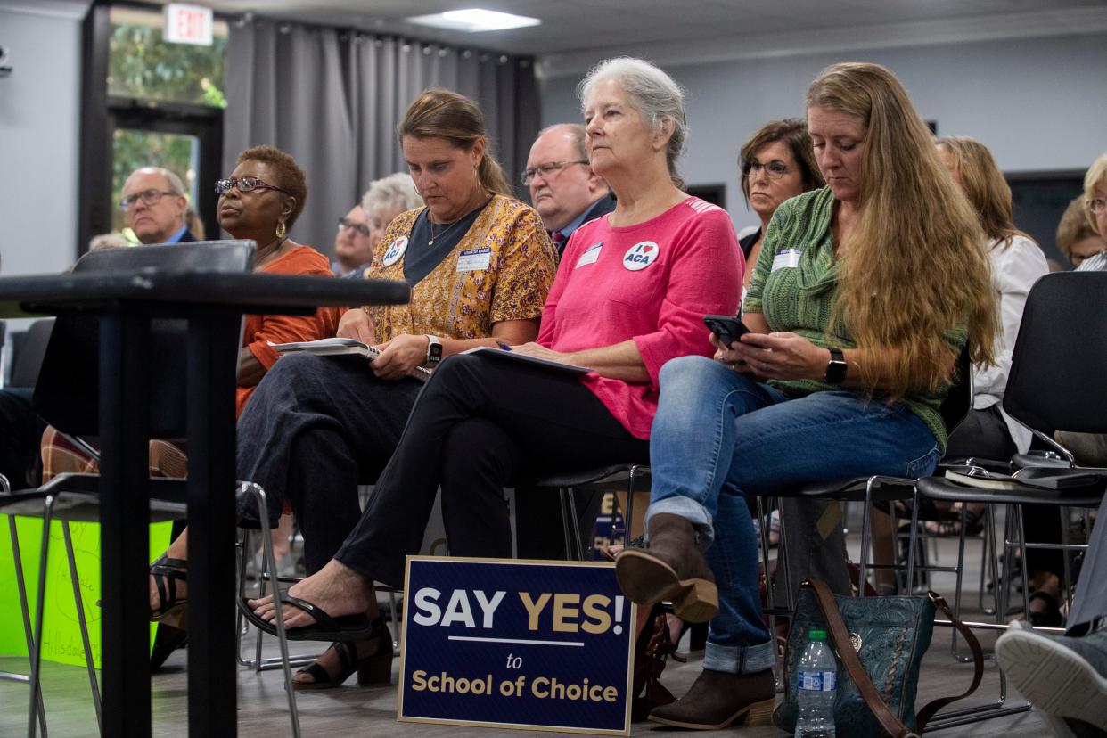 Tanna Keel, Mary Bowen and Donna Thomas listen to a speaker while wearing buttons and having signs next to them in favor of ACA during the American Classical Academy Madison County Charter School Appeal Public Hearing on Thursday, September 15, 2022, in Jackson, Tenn. 