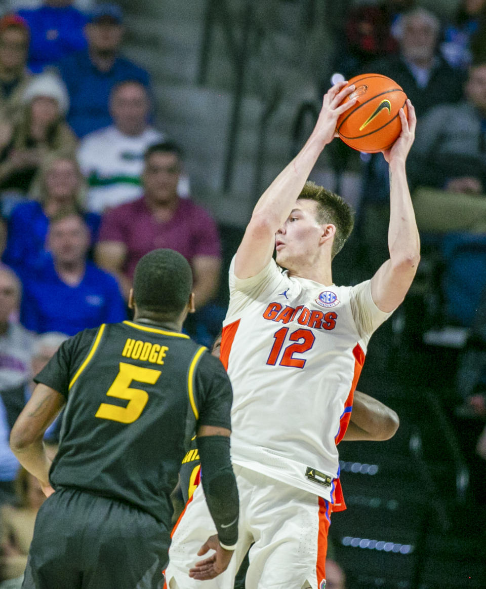 Florida forward Colin Castleton (12) tries to pass around Missouri guard D'Moi Hodge (5) during the first half of an NCAA college basketball game Saturday, Jan. 14, 2023, in Gainesville, Fla. (AP Photo/Alan Youngblood)