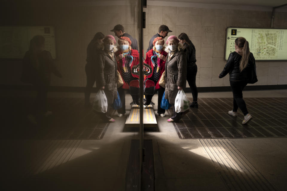 People, some of them wearing face masks to protect against coronavirus, are reflected in a marble wall of an underpass as they walk in Moscow, Russia, Monday, April 19, 2021. (AP Photo/Alexander Zemlianichenko)