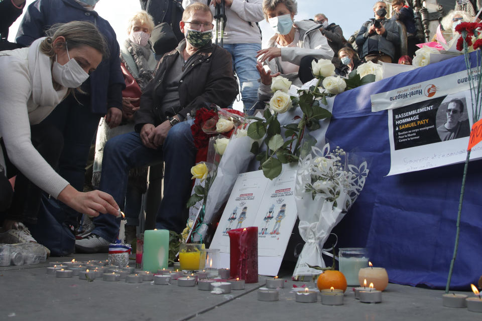 A woman lights a candle on Republique square during a demonstration Sunday Oct. 18, 2020 in Paris. Demonstrations around France have been called in support of freedom of speech and to pay tribute to a French history teacher who was beheaded near Paris after discussing caricatures of Islam's Prophet Muhammad with his class. Samuel Paty was beheaded on Friday by a 18-year-old Moscow-born Chechen refugee who was shot dead by police. (AP Photo/Michel Euler)