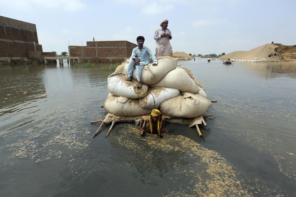 Flood victims from monsoon rain use a makeshift barge to carry hay for cattle, in Jaffarabad, a district of Pakistan's southwestern Baluchistan province, on Sept. 5, 2022. (AP Photo/Fareed Khan)