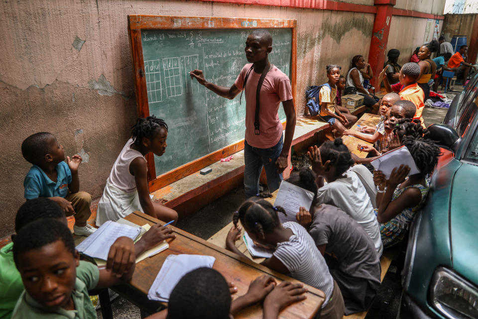 A man teaches math to children living in a shelter for families who fled their homes amid gang violence in Port-au-Prince., Haiti, Monday, May 27, 2024. (AP Photo/Odelyn Joseph)