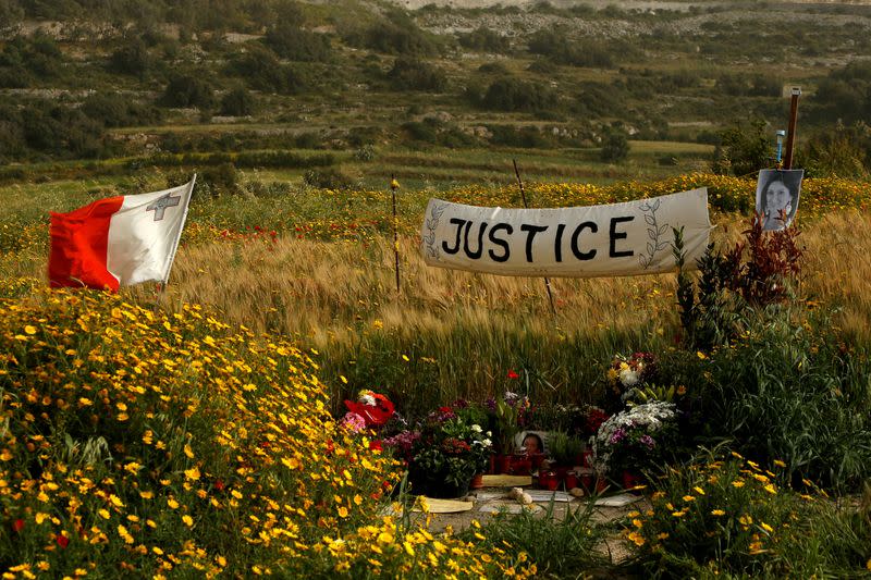 FILE PHOTO: A banner calling for justice is seen next to a photo of assassinated anti-corruption journalist Daphne Caruana Galizia at the bomb site, as Maltese prepare to mark six months since her murder, in Bidnija