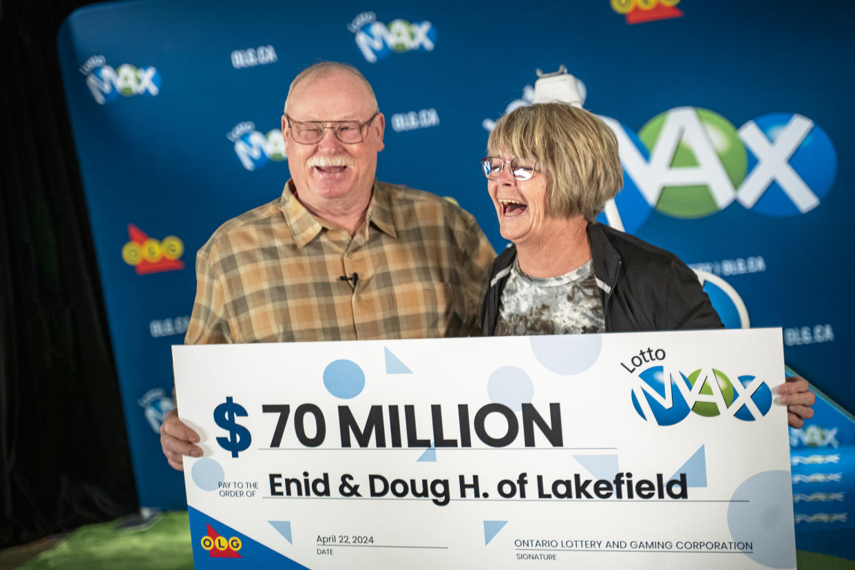 Older couple holding a $70 million lotto cheque