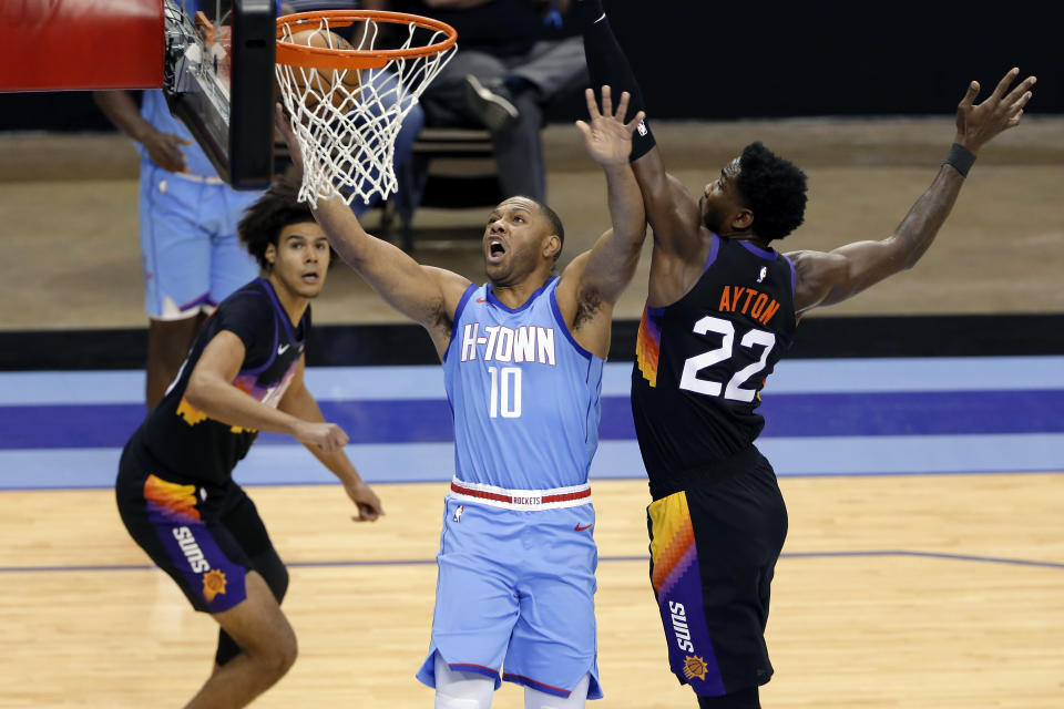 Houston Rockets guard Eric Gordon (10) shoots past Phoenix Suns center Deandre Ayton (22) as forward Cameron Johnson, left, looks on during the first half of an NBA basketball game, Wednesday, Jan. 20, 2021, in Houston. (AP Photo/Michael Wyke)