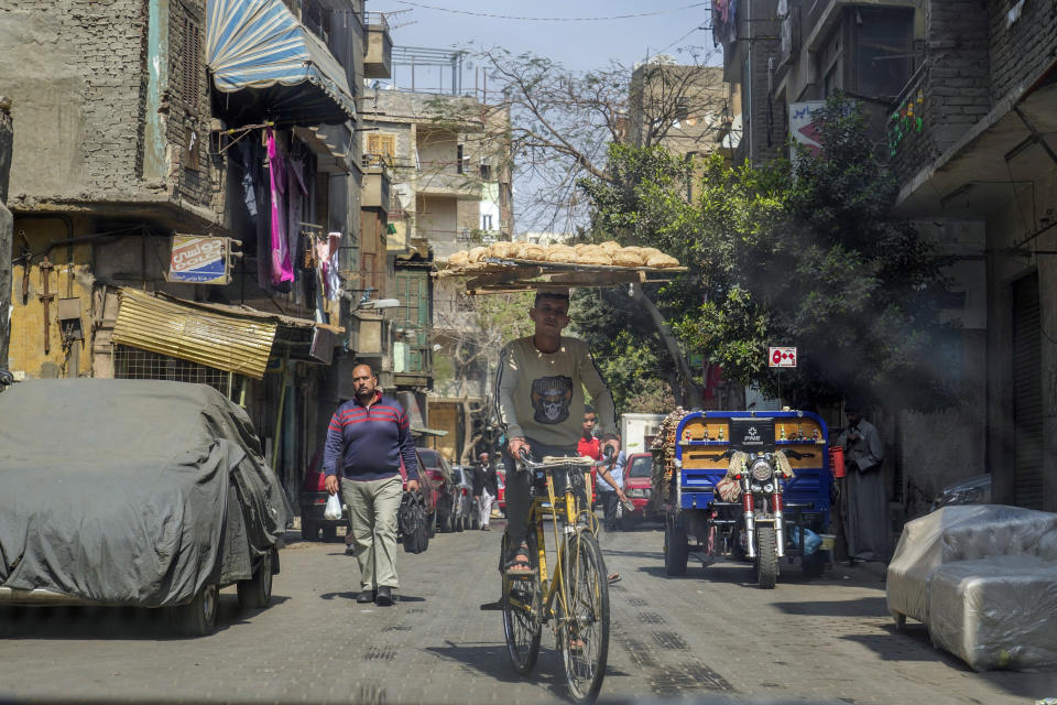 An Egyptian vendor balances a tray of bread as he cycles in Old Cairo, Egypt, Tuesday, March 21, 2023. Egypt is embarking on a privatization push to help its cash-strapped government, after pressure from the International Monetary Fund. The new policy is supposed to be a serious departure for the Egyptian state, which has long maintained a tight grip over sectors of the economy. (AP Photo/Amr Nabil)