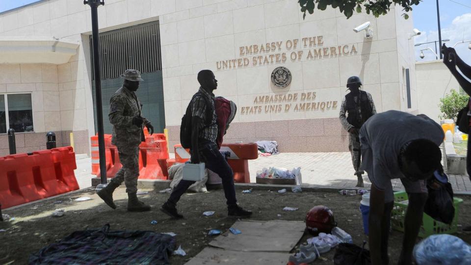 PHOTO: A man carries his belongings after officers of the Haitian National Police fired tear gas to clear a camp of people escaping the threat of armed gangs, in front of the U.S. Embassy, in Port-au-Prince, Haiti, on July 25, 2023. (Ralph Tedy Erol/Reuters)