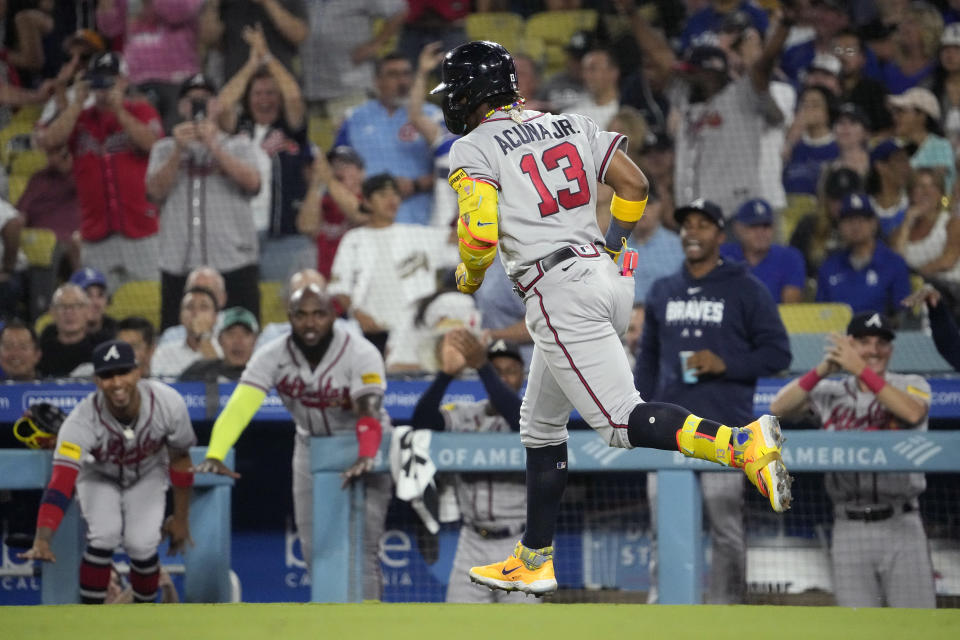 Atlanta Braves' Ronald Acuna Jr. heads to first after hitting a grand slam as teammates celebrate from the bench during the second inning of a baseball game against the Los Angeles Dodgers Thursday, Aug. 31, 2023, in Los Angeles. (AP Photo/Mark J. Terrill)