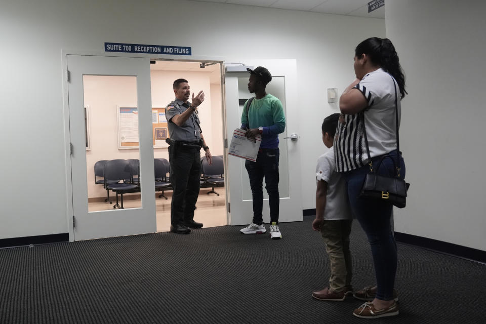 An officer directs people to a courtroom, Wednesday, Jan. 10, 2024, in an immigration court in Miami. Immigration courts are buckling under an unprecedented 3 million pending cases, most of them newly arrived asylum-seekers. The number of migrants trying to fight their deportation in front of a US judge has grown by 50% in less than a year. (AP Photo/Wilfredo Lee)