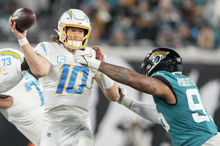 Los Angeles Chargers quarterback Justin Herbert (10) works in the pocket as Jacksonville Jaguars defensive end Roy Robertson-Harris (95) defends during the second half of an NFL wild-card football game, Saturday, Jan. 14, 2023, in Jacksonville, Fla. (AP Photo/Chris Carlson)