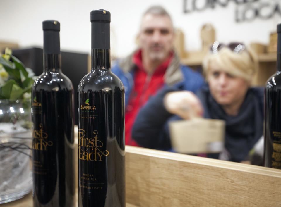 Visitors look at bottles of local wine "First Lady" displayed for visitors in Sevnica, Slovenia, Friday, Jan. 20, 2017. The inauguration of Donald Trump is a big thing for a small town in Slovenia where the future U.S. first lady traces her roots. Starting Friday, the industrial town of Sevnica plans three days of events to mark the inauguration and welcome all guests wishing to see where Melania Trump grew up. (AP Photo/Darko Bandic)