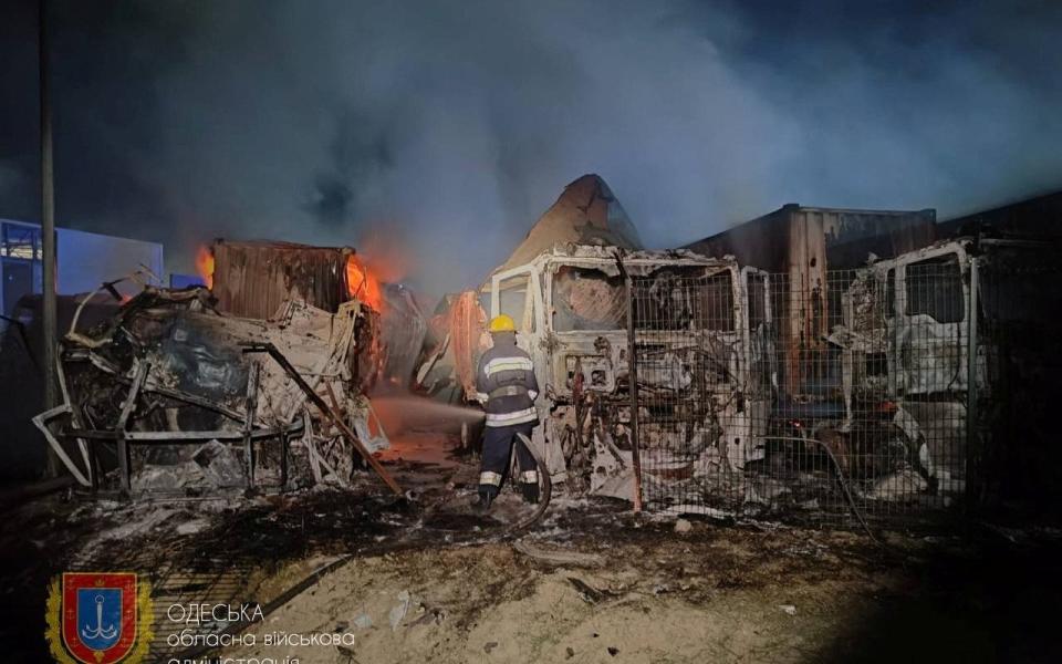 Firefighters work near damaged trucks following a Russian strike, amid Russia's attack on Ukraine