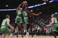 Toronto Raptors forward Scottie Barnes (4) jumps with Boston Celtics center Al Horford (42) and forward Oshae Brissett (12) for control of the ball during first-half NBA basketball game action in Toronto, Monday Jan. 15, 2024. (Nathan Denette/The Canadian Press via AP)