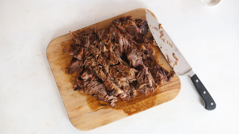sliced pot roast on cutting board with knife