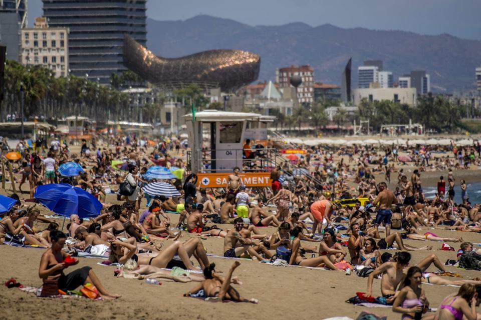 People sunbathe on the beach in Spain