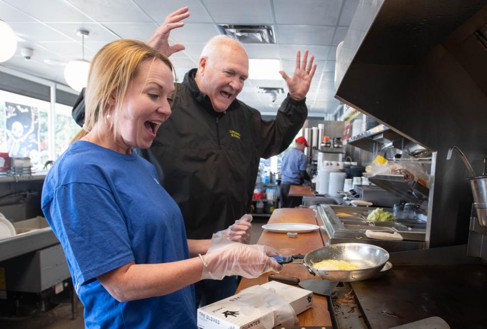 Bert Thornton, Waffle House vice chairman emeritus, right, cheers on KC Gartman, Baptist Health Care chief development officer, as she successfully flips eggs while training at the Waffle House on Brent Lane in Pensacola on Monday, Oct. 16, 2023.