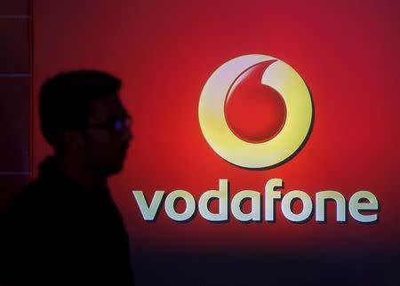 A man casts silhouette onto an electronic screen displaying logo of Vodafone India after a news conference to announce the half year results in Mumbai, India, November 10, 2015. REUTERS/Shailesh Andrade/File Photo