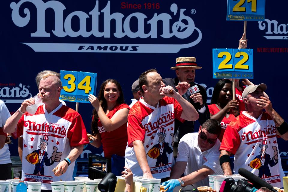 Joey Chestnut, center, competes in the Nathan’s Famous Fourth of July hot dog eating contest in Coney Island, New York. Chestnut ate 63 hot dogs to win the men's division of the contest.