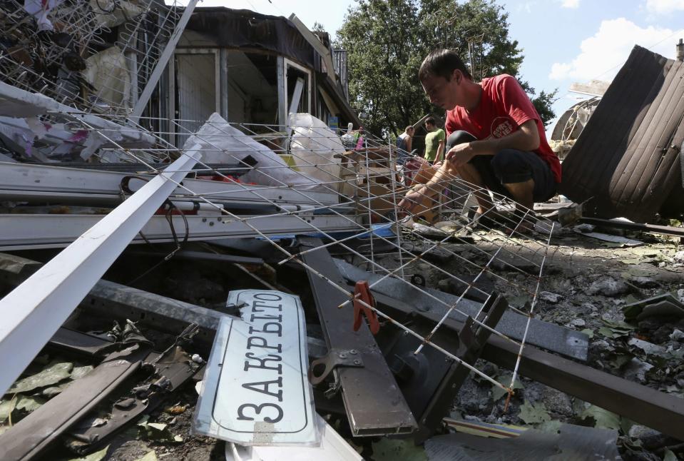 A man inspects wreckage near a damaged building following what locals say was a recent airstrike by Ukrainian forces in Donetsk, August 6, 2014. The sign reads "Closed". REUTERS/Sergei Karpukhin (UKRAINE - Tags: MILITARY CONFLICT CIVIL UNREST)