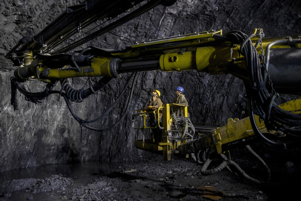 Kashmiri worker Tariq Ahmed Lone, wearing blue helmet, stands on a crane along with other worker employed by the Megha Engineering And Infrastructures Limited (MEIL) works inside the Nilgrar Tunnel in Baltal area northeast of Srinagar, Indian controlled Kashmir, Tuesday, Sept. 28, 2021. High in a rocky Himalayan mountain range, hundreds of people are working on an ambitious project to drill tunnels and construct bridges to connect the Kashmir Valley with Ladakh, a cold-desert region isolated half the year because of massive snowfall. The $932 million project’s last tunnel, about 14 kilometers (9 miles) long, will bypass the challenging Zojila pass and connect Sonamarg with Ladakh. Officials say it will be India’s longest and highest tunnel at 11,500 feet (3,485 meters). (AP Photo/Dar Yasin)