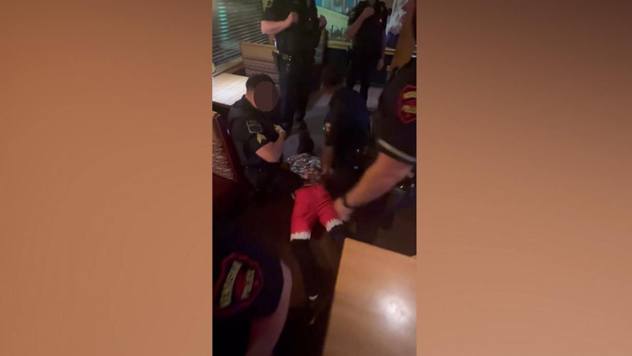 PHOTO: In this screen grab from bodycam video, a man is arrested while holding a baby in an Applebee's in Kenosha, Wis., on July 20, 2023. (Hal Mudge)