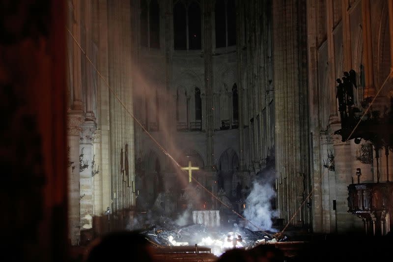 FILE PHOTO: Smoke rises around the altar in front of the cross inside the Notre Dame Cathedral as a fire continues to burn in Paris