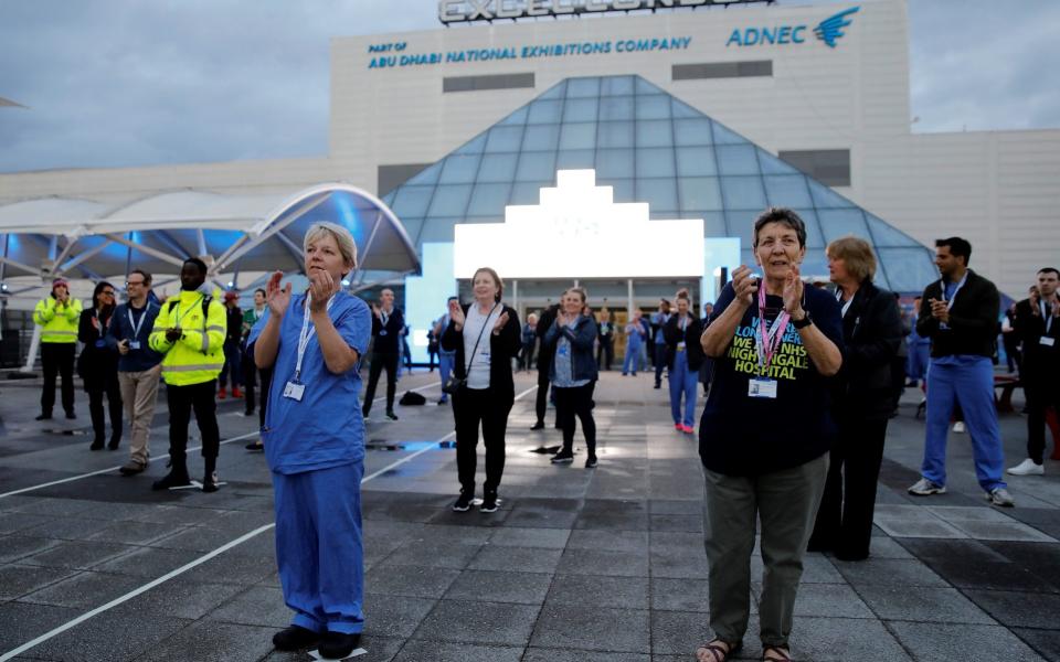 Medical staff and workers take part in a national "clap for carers" outside the ExCeL London exhibition centre, which was transformed into the NHS Nightingale field hospital in London - Tolga Akmen/Getty Images