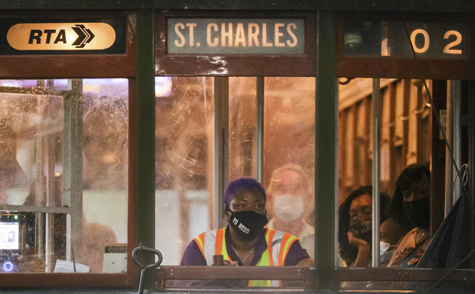 A masked conductor rolls along South Carrollton Ave. in New Orleans, Tuesday, Aug. 3, 2021. (David Grunfeld/The Times-Picayune/The New Orleans Advocate via AP)