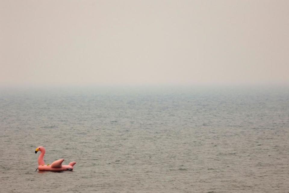 A giant inflatable flamingo floats on Lake Tahoe as smoke from the Caldor fire is thick in the air.