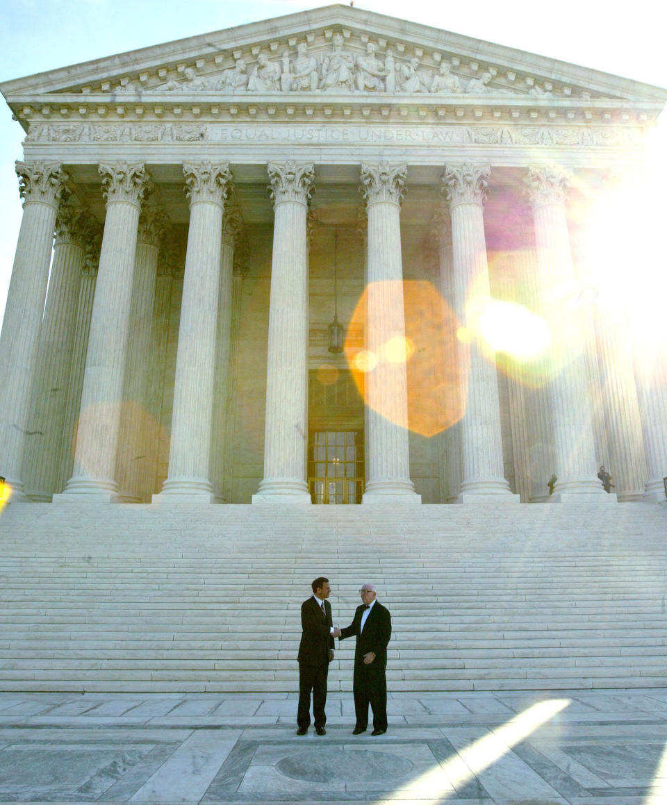 Chief Justice John Roberts (left) and Justice Stevens pose for photographers outside the U.S. Supreme Court after Roberts' investiture ceremony on Oct. 3, 2005.