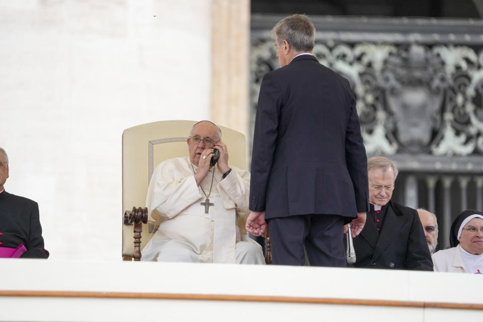 Pope Francis talks on the phone during his weekly general audience in the St. Peter's Square at the Vatican, Wednesday, May 17, 2023. (AP Photo/Andrew Medichini)
