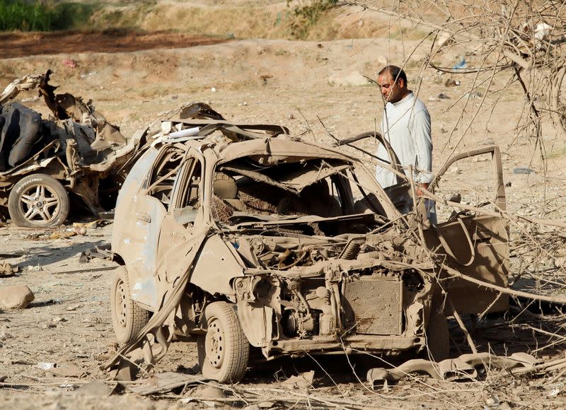 FILE PHOTO: An Afghan man inspects the wreckage of a car at the site of a truck bomb blast in Ghani Khel district of Nangarhar province