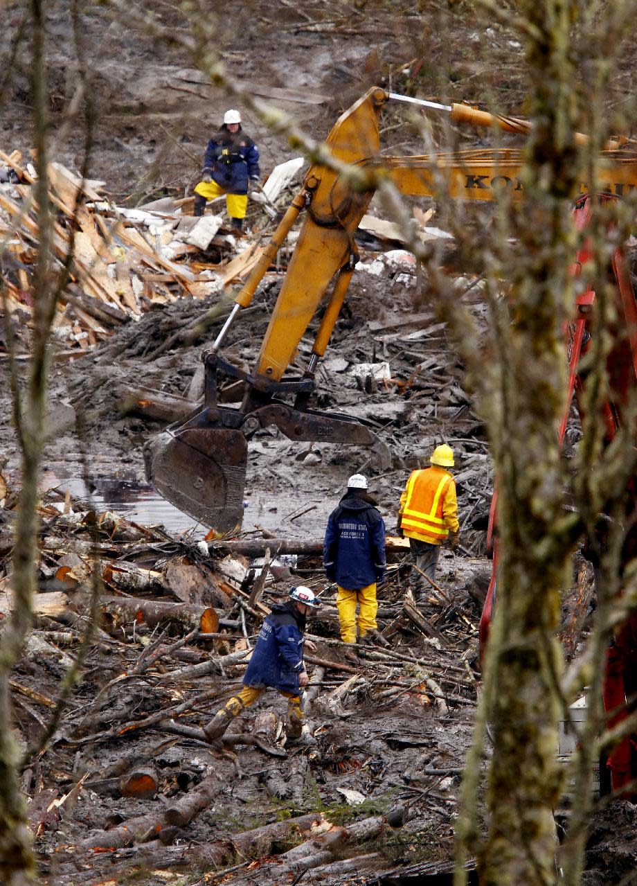 Searchers using heavy equipment work at a massive pile of debris at the scene of a deadly mudslide, Thursday, March 27, 2014, in Oso, Wash. The death toll is expected to rise considerably within the next two days as the Snohomish County Medical Examiner's Office catches up with the recovery effort, Snohomish County District 21 Fire Chief Travis Hots said Thursday. (AP Photo/The Herald, Mark Mulligan, Pool)