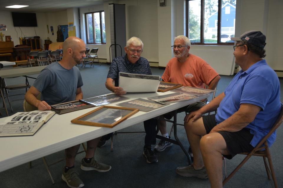 Roof Garden Barbershop Chorus members from left: Lee Hoffman, Larry Shober, Stu Kreinbrook and Dave Emert look over group photographs over the years.