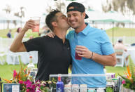 <p>Wells Adams plants a kiss on fellow <em>Bachelor</em> alum Ben Higgins behind a pop up bar at the Hilton Grand Vacations Tournament of Champions in Orlando. </p>