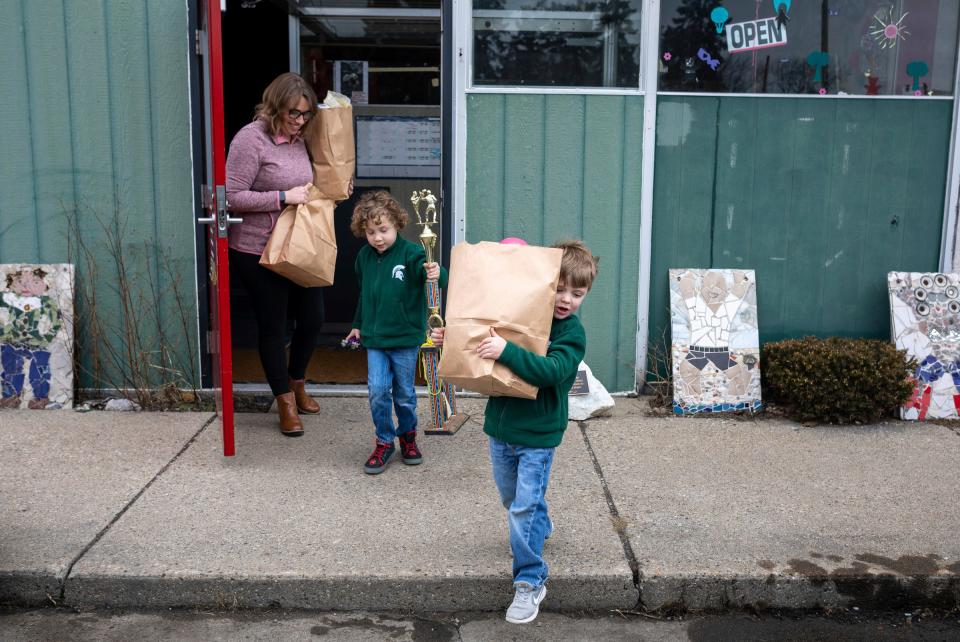 April Beaton holds two paper bags full of items after shopping alongside her 5-year-old son, Alex Lynn and 4-year-old son, Jacob Lynn, inside Arts & Scraps in Detroit on Friday, Feb. 16, 2024. Lynn adopted Alex and Jacob out of foster care and has learned what kind of support they need to thrive despite the various ways adverse childhood experiences have played out in their lives.