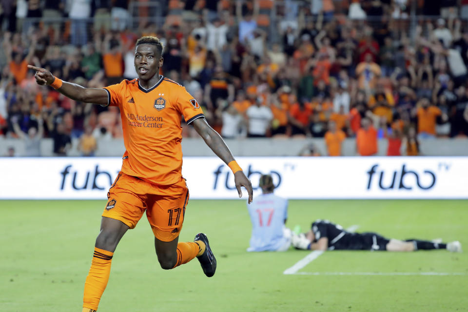 Houston Dynamo defender Teenage Hadebe (17) celebrates his goal against FC Dallas' Nkosi Tafari (17) and goalkeeper Maarten Paes, right, during the second half of an MLS soccer match Saturday, July 9, 2022, in Houston. (AP Photo/Michael Wyke)