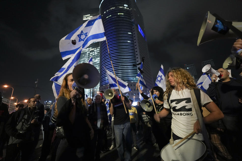 Israelis chant slogans and wave the national flag during a protest against the plans by Prime Minister Benjamin Netanyahu's new government to overhaul the judicial system, in Tel Aviv, Israel, Saturday, Jan. 28, 2023. (AP Photo/Tsafrir Abayov)