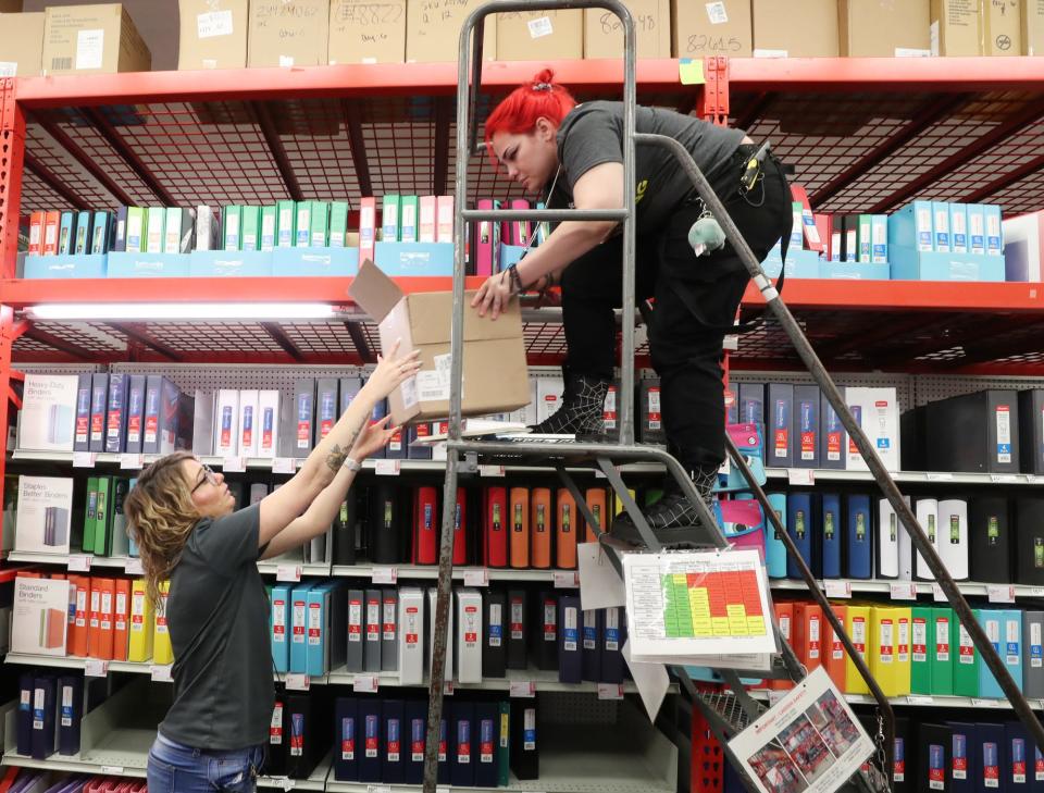 Alyssa Jordan, operations manager, hands a box of binders to Riley Nash, an inventory specialist, at Staples on Arlington Road in Akron on Monday, July 18, 2022.